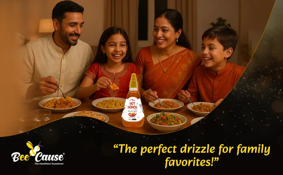 A happy Indian family (mother, father, son, and daughter) smiling while enjoying dinner together with a bottle of Bee Cause Hot Honey sauce prominently displayed on the table. Text overlay reads: "The perfect drizzle for family favorites