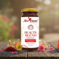 Bee Cause Beauty Blend superfood jar on a wooden surface with flowers in the background