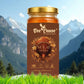 A single jar of Bee Cause Sulai Honey, labeled as authentic and unprocessed, set against a backdrop of majestic snow-capped mountains and a pine forest valley.