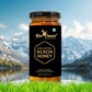 A single jar of Bee Cause Pure & Natural Acacia Honey displayed prominently in front of a scenic background featuring a calm lake and snow-capped mountains.