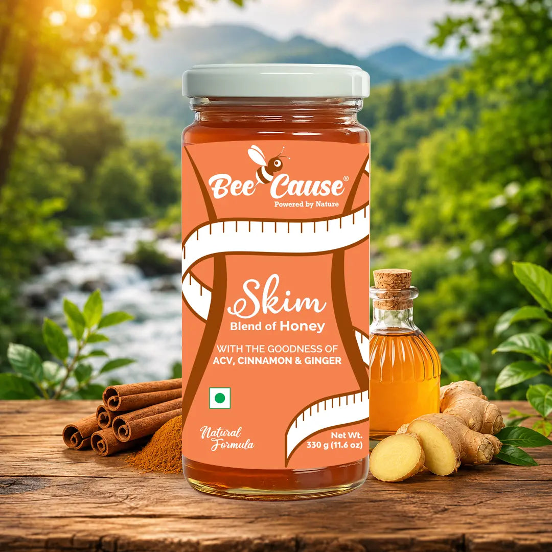A jar of Bee Cause Skim Blend of Honey is displayed on a rustic wooden table with ingredients like cinnamon sticks, ginger, and a small bottle of honey, set against a blurred natural forest background.