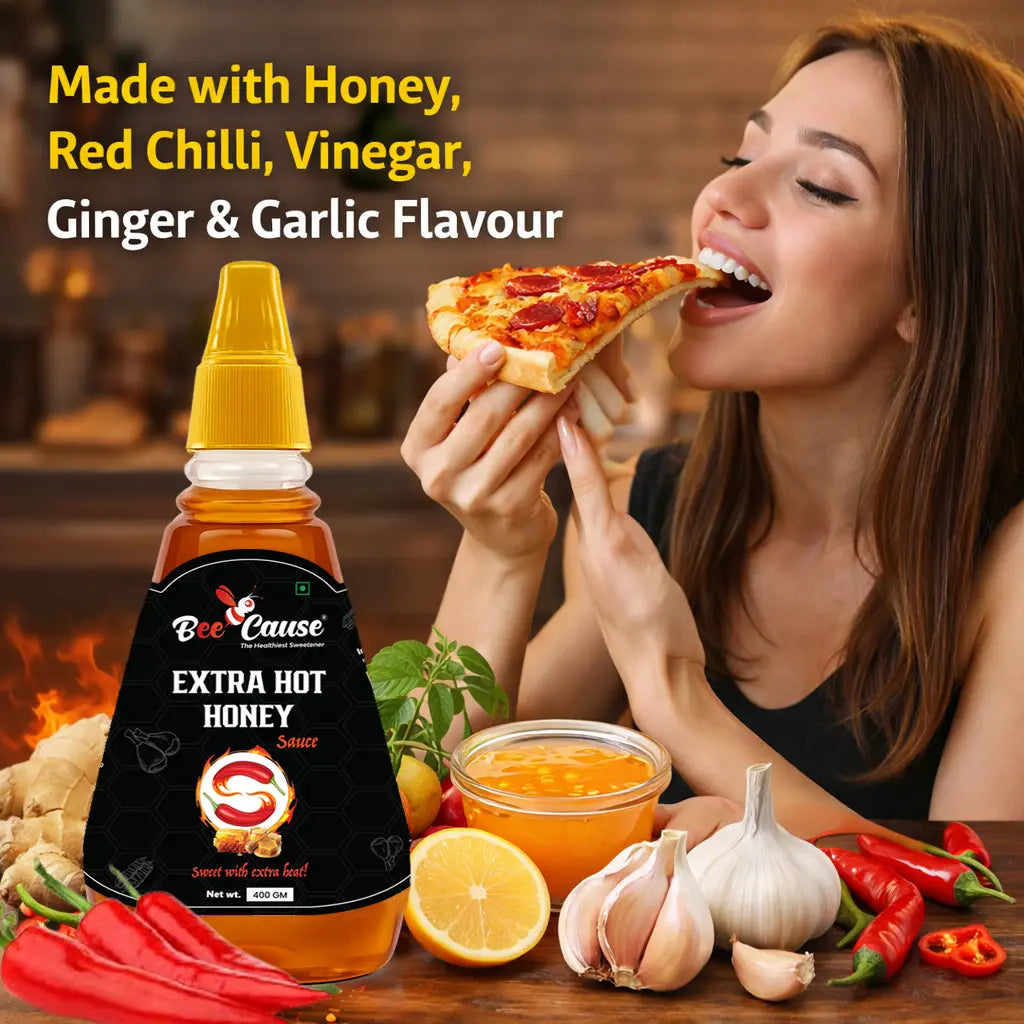 A woman smiling while taking a bite of a pepperoni pizza slice, with a bottle of Bee Cause Extra Hot Honey Sauce in the foreground. Bold text reads "Made with Honey, Red Chilli, Vinegar, Ginger & Garlic Flavour," surrounded by fresh ingredients including red chilies, half a lemon, garlic cloves, and a bowl of the sauce.