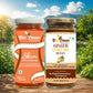 Two glass jars of Bee Cause honey displayed side by side on a wooden surface with a scenic outdoor background of green foliage, a lake, and a blue sky. The left jar is labeled 'Skim Blend of Honey' with an orange and white label, and the right jar is labeled 'Ginger Curcumin Honey' with a white, brown, and gold label.