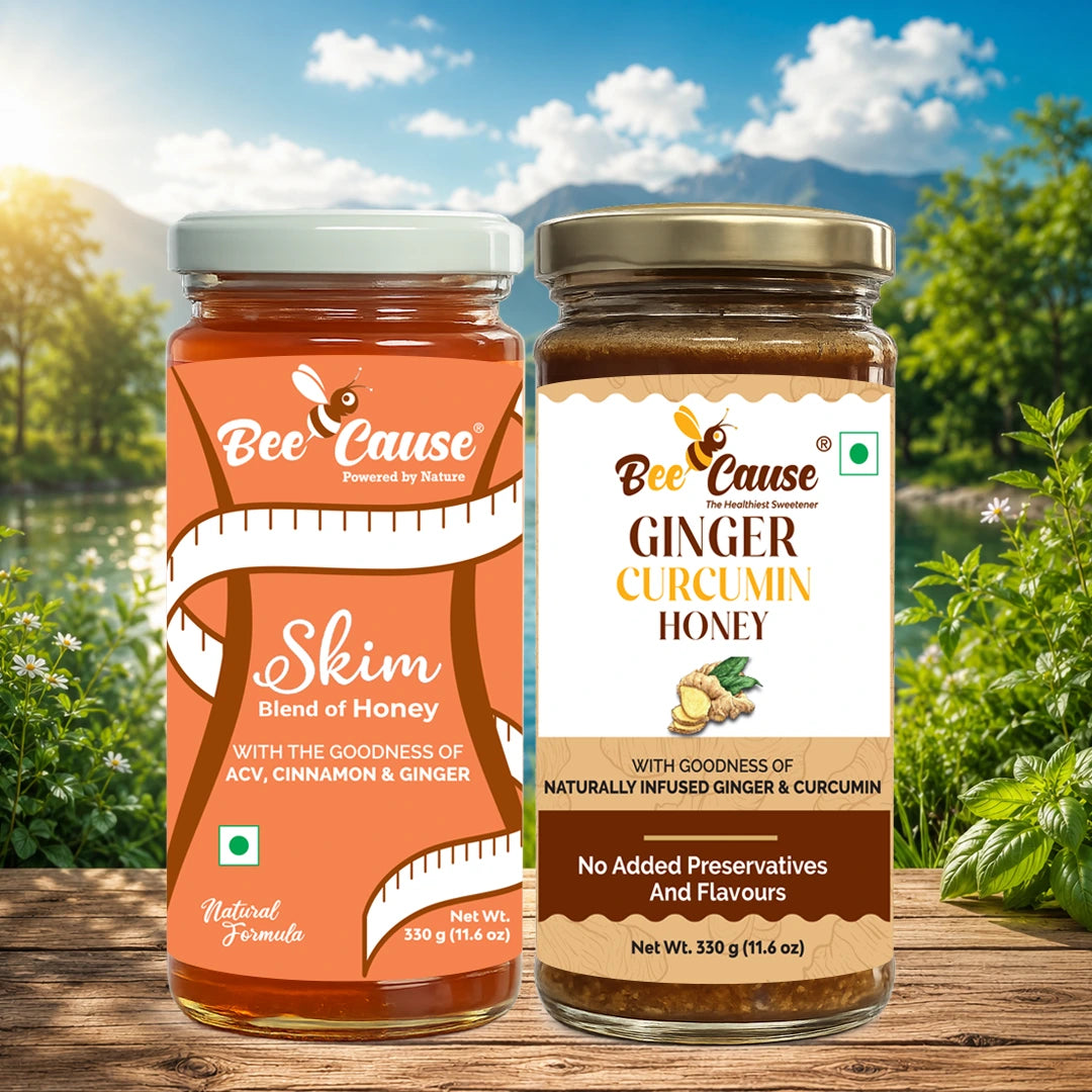Two glass jars of Bee Cause honey displayed side by side on a wooden surface with a scenic outdoor background of green foliage, a lake, and a blue sky. The left jar is labeled 'Skim Blend of Honey' with an orange and white label, and the right jar is labeled 'Ginger Curcumin Honey' with a white, brown, and gold label.