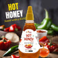 A close-up action shot of a person pouring Bee Cause Hot Honey Sauce directly onto a slice of fresh pepperoni pizza. Large text reads "HOT HONEY ON PIZZA" with a smaller tagline below saying "A slice of heaven with a kick of heat!"