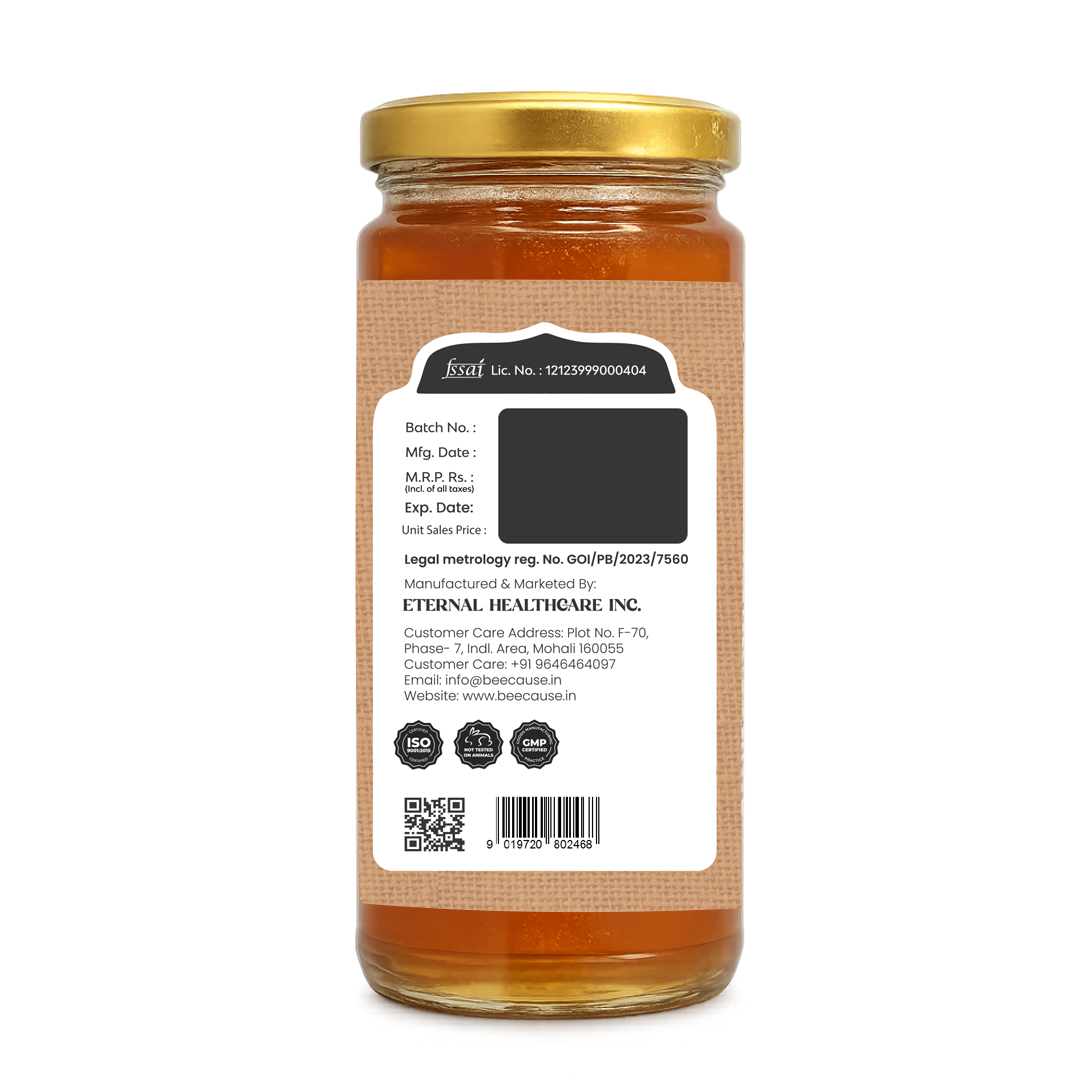 The back of a glass jar of honey with a gold metal lid, showing a detailed white label with text and a barcode, set against a plain white background.