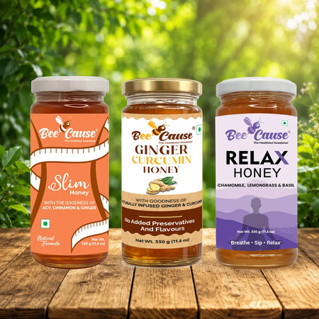Three jars of 'Bee Cause' honey with different flavors on a wooden surface with a natural background.