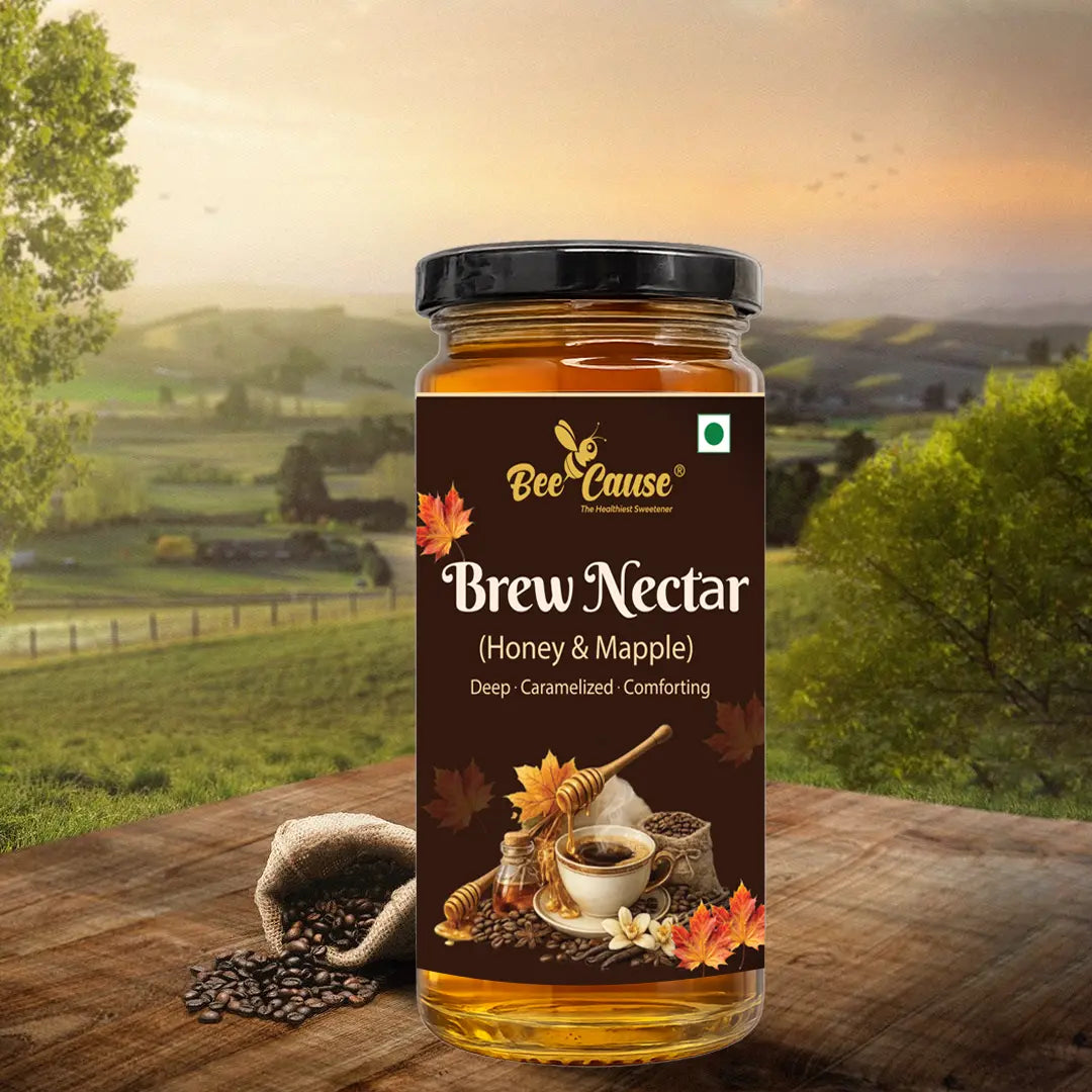 A jar of Bee Cause Maple Brew Nectar displayed on a wooden table alongside coffee beans and maple leaves, set against a rolling countryside landscape at sunset