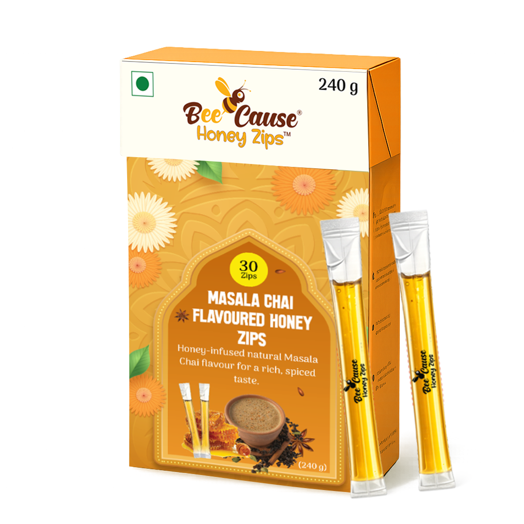 A 240-gram box of Bee Cause Masala Chai Flavoured Honey Zips featuring a yellow and orange floral design, displayed with two individual honey sticks leaning against it.