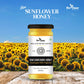 A stunning product shot of Bee Cause Raw Sunflower Honey set against a vibrant field of blooming sunflowers under a clear blue sky.
