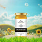 A scenic product display of Bee Cause Raw Sunflower Honey placed on a wooden platform against a bright blue sky and green field background, symbolizing natural freshness.