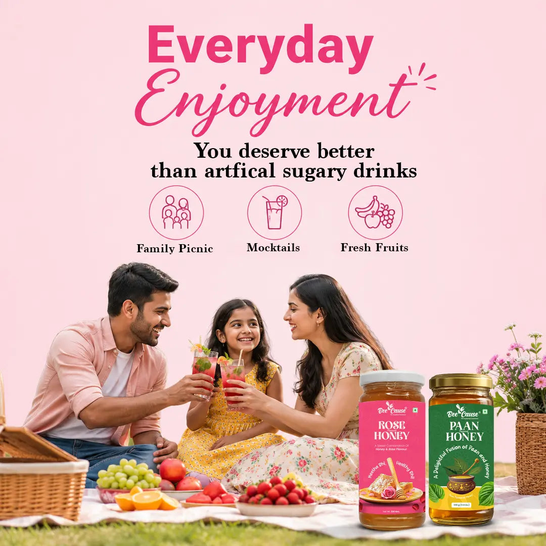 A lifestyle advertisement featuring a family picnic scene with two adults and a child holding a drink, set against a pink background with promotional text. In the foreground, two jars of Brij Bhawan Honey are displayed: 'Home Honey' in pink packaging and 'Paan Honey' in green packaging, with fresh fruits like strawberries, grapes, and oranges on a picnic blanket.