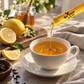 BeeCause Lemon Honey Zips pouring honey into a warm cup of tea with fresh lemon