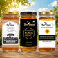 Three glass jars of Bee Cause honey arranged on a wooden surface outdoors, with a blurred sky and greenery background. The left jar is Raw Golden Honey, the center jar is Acacia Honey, and the right jar is Raw Sunflower Honey.