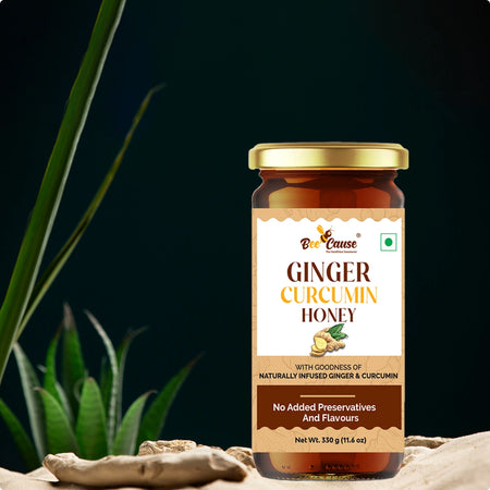 An aesthetic, high-quality product shot of Bee Cause Ginger Curcumin Honey placed on a textured stone surface with dark greenery in the background.