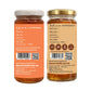 Two glass jars of honey shown side by side on a white background, displaying the front and back labels of the product. The honey inside is a rich amber-brown color, and the labels are orange and beige respectively, with white and gold lids.