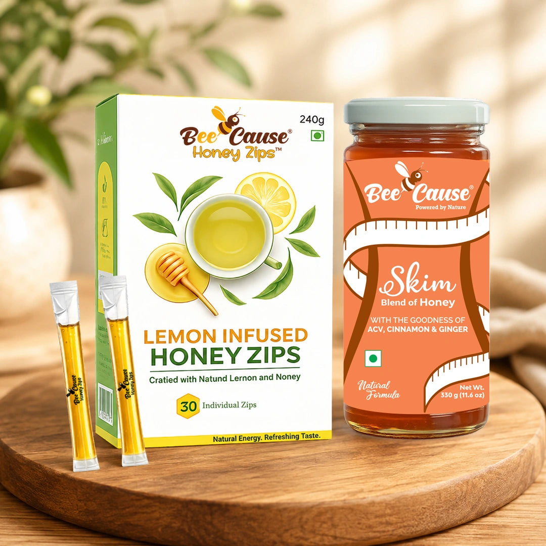 Bee Cause Lemon Infused Honey Zips packaging shown with two individual zips and a jar of honey on a wooden tray, set against a softly blurred warm background.
