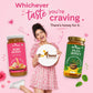 A woman in a pink floral dress stands between two jars of Bee Cause honey on a pink background, holding a round sign that reads 'Bee Cause'. The left jar is labeled Rose Honey with a pink label, and the right jar is labeled Paan Honey with a green label.