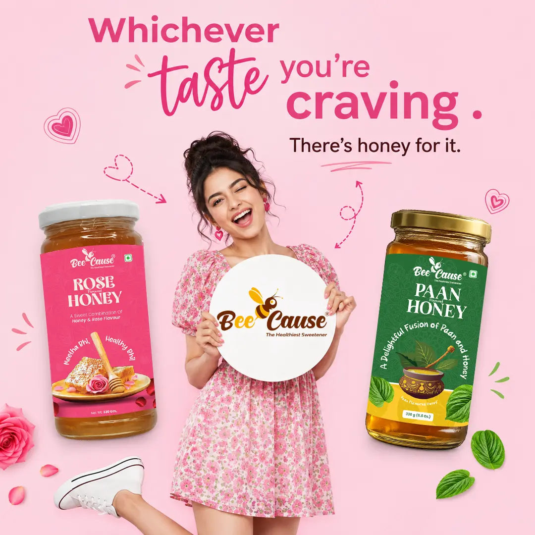 A woman in a pink floral dress stands between two jars of Bee Cause honey on a pink background, holding a round sign that reads 'Bee Cause'. The left jar is labeled Rose Honey with a pink label, and the right jar is labeled Paan Honey with a green label.